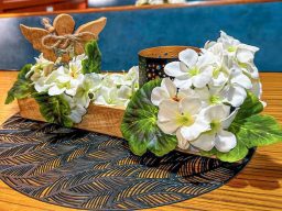 Ein gemütlicher Innenraum der MS Ol Büsum mit blauen Sitzen und Tischen, dekoriert mit Blumen.