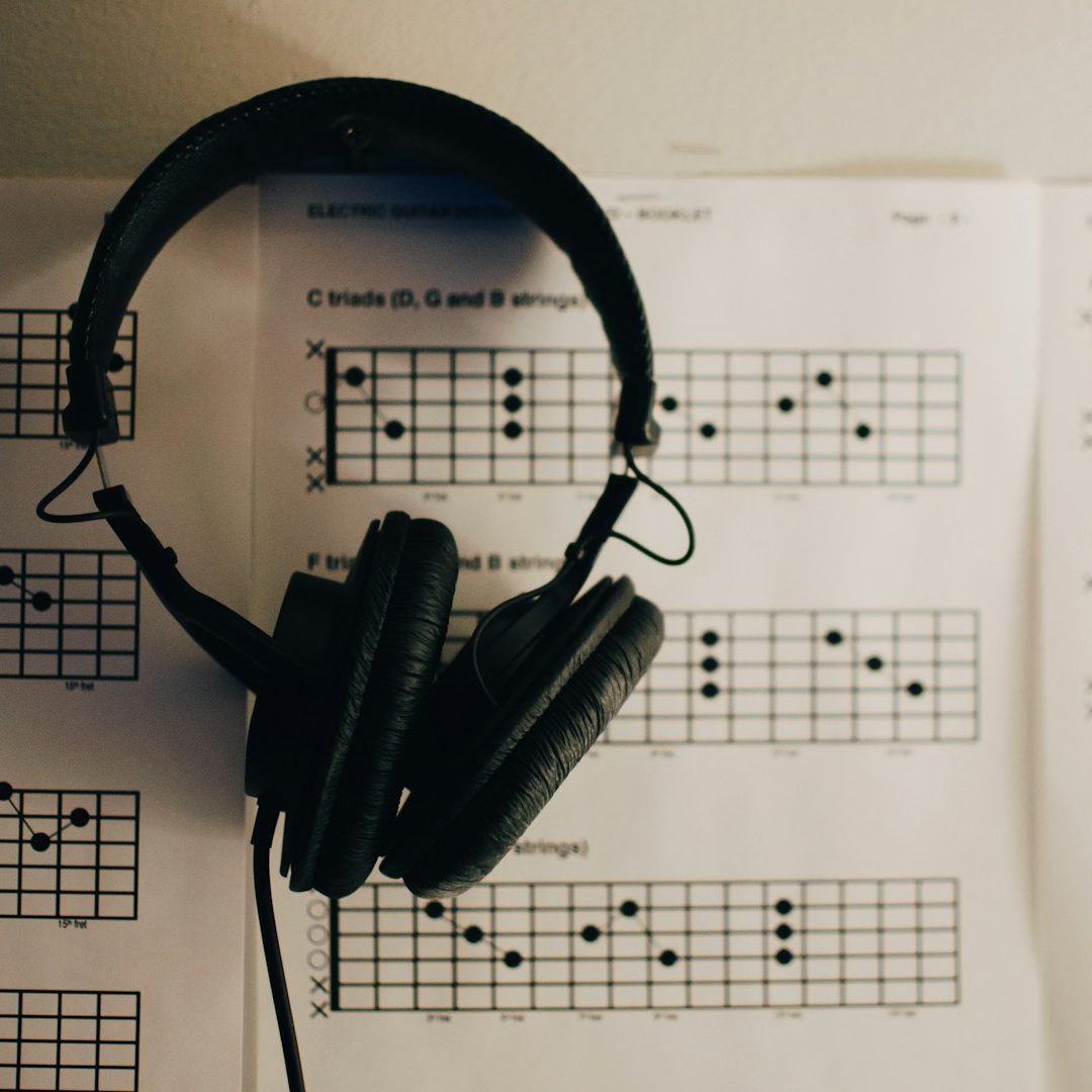 Kopfhörer liegen auf Notenblättern mit Akkorden und Musiknotation.