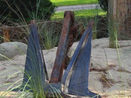 Rostiger Anker, umgeben von Sand und Gras auf der kleinen Düne