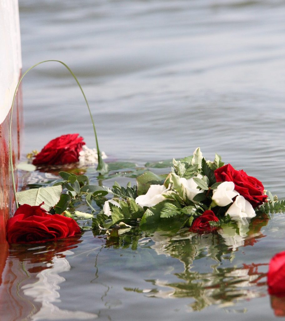 Ein Kranz aus roten und weißen Rosen schwimmt im Wasser.