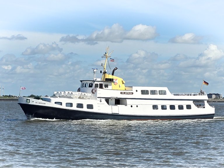 MS Ol Büsum, weiß-blaues Passagierschiff, fährt auf ruhigem Wasser mit Wolken am Himmel.