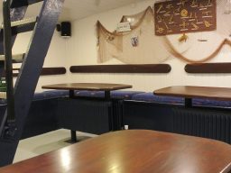 Gemütlicher Innenraum mit Tischreihen und dekorativen Elementen an der Wand.